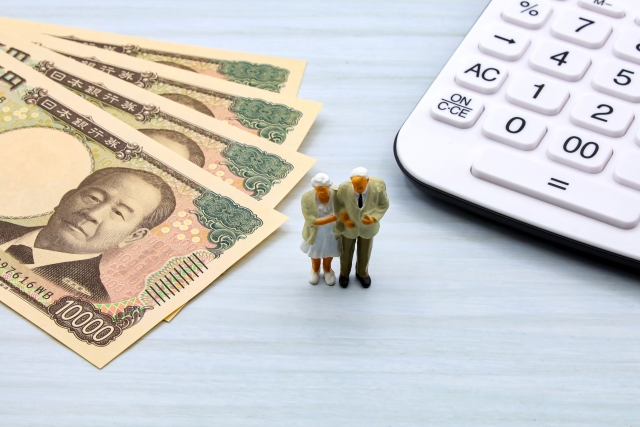 Japanese yen banknotes, small figurines of an elderly couple, and a calculator.