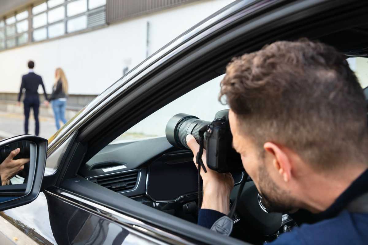 Investigator from inside a car taking a surveillance photo of a couple walking down the street.