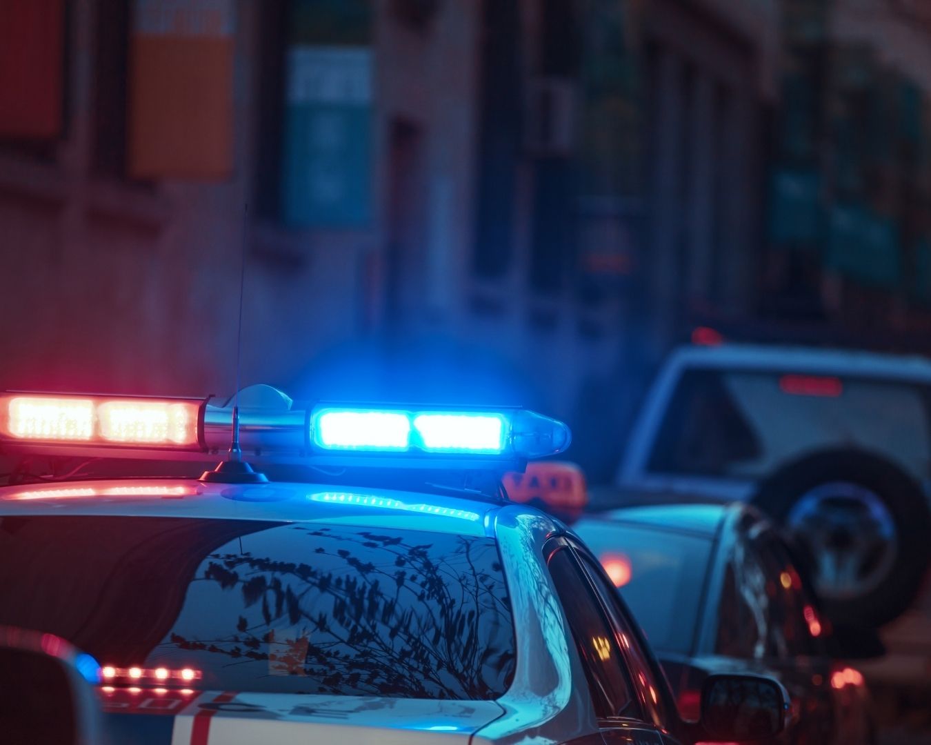 Two investigators in a car, one taking photos with a large camera lens.
