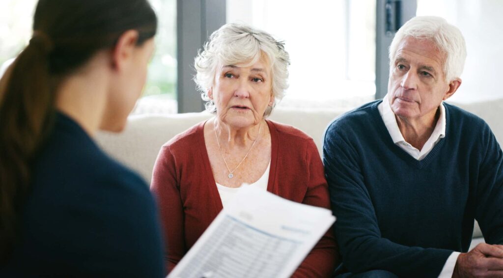 An elderly couple looking concerned while listening to a consultant.