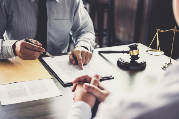 A lawyer pointing to a document while consulting with a client, with a gavel on the table.