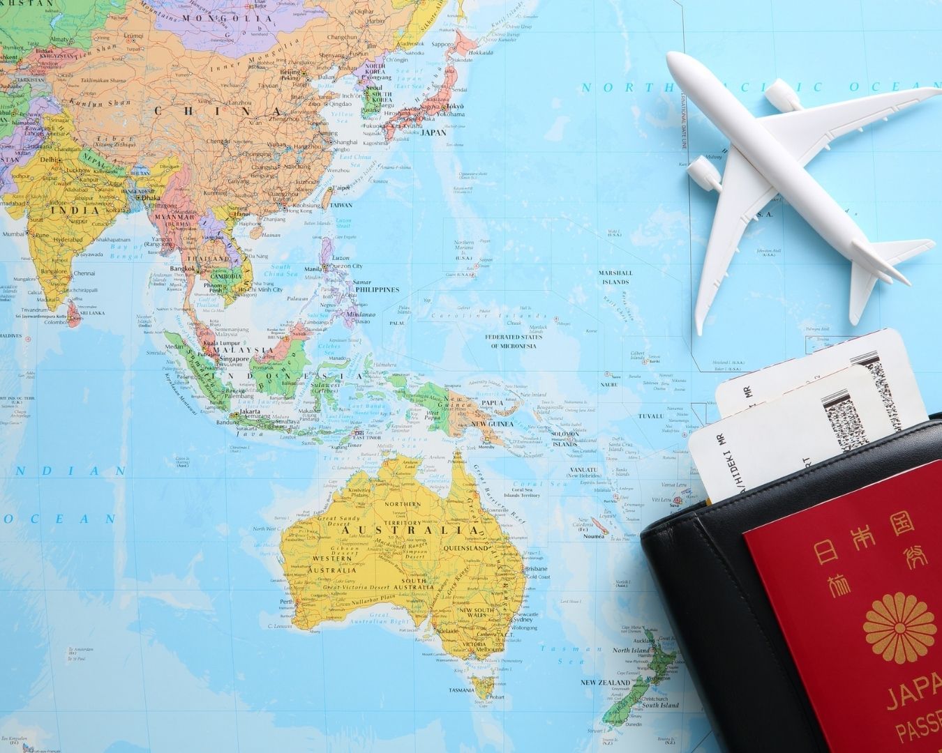 Map of Asia and Australia with a Japanese passport and airplane model.