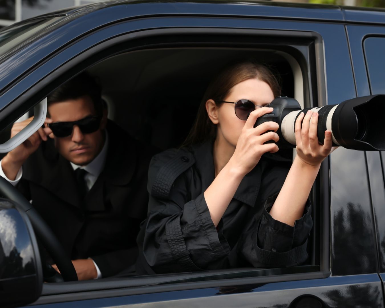 Silhouette of an investigator with binoculars and a camera on a tripod.