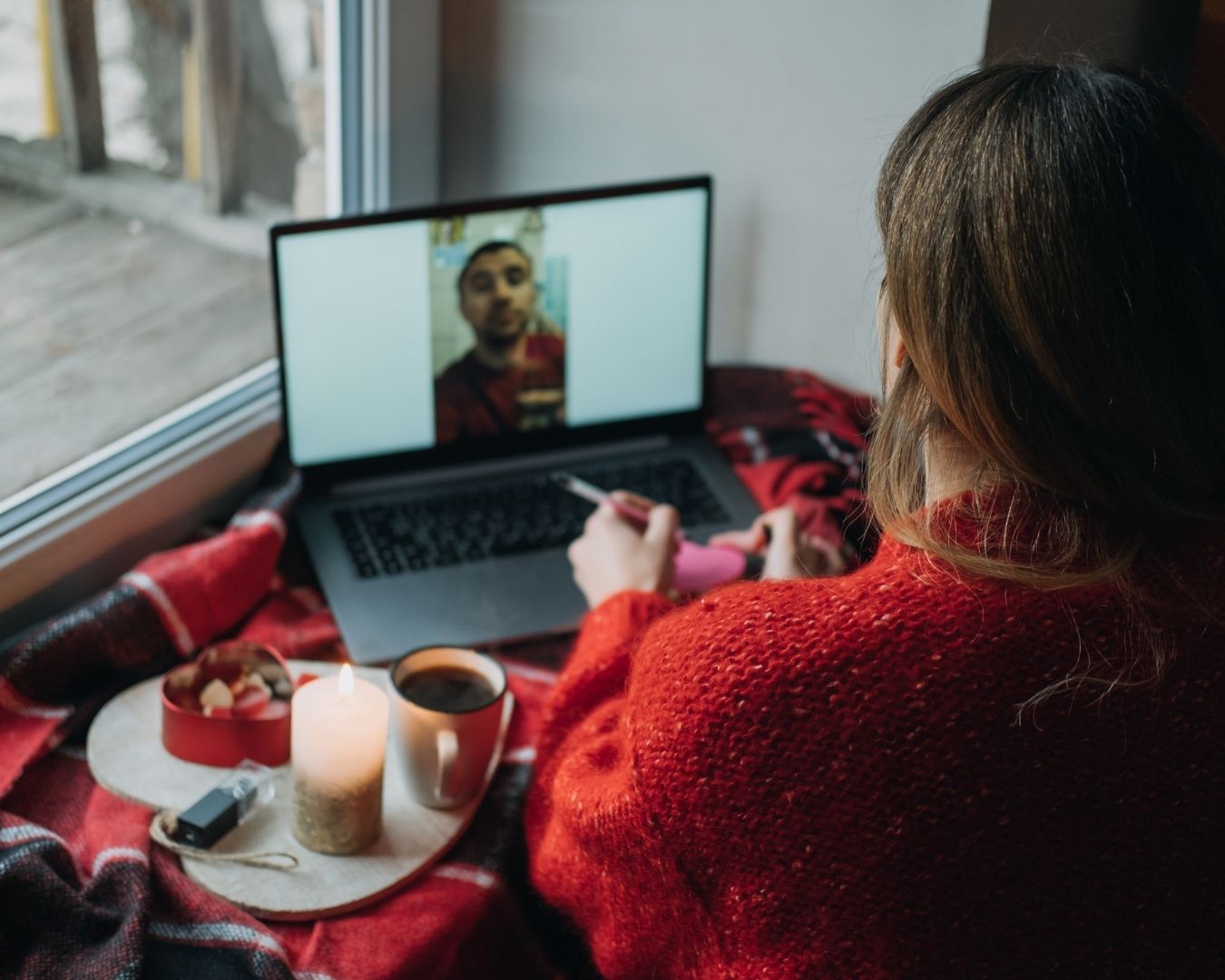 Woman in a red sweater on a video call on her laptop.