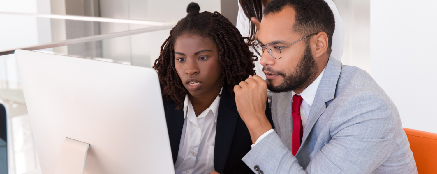 Two colleagues looking intently at a computer screen together.