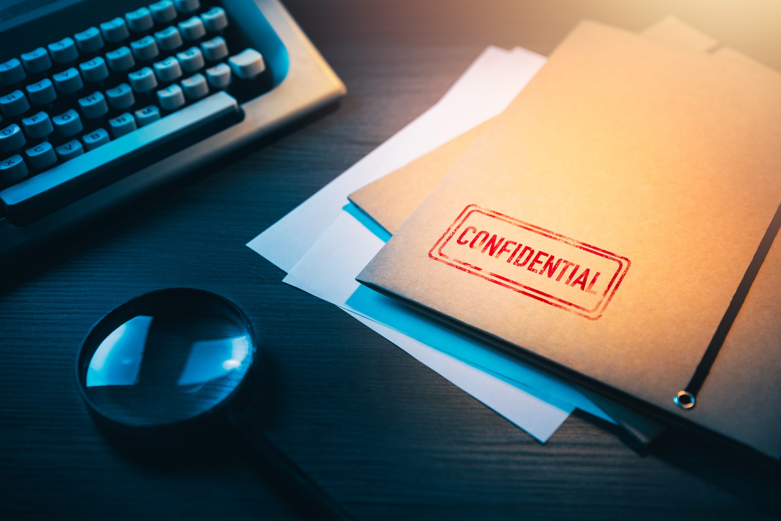 A confidential folder on a dark desk with a magnifying glass and typewriter.