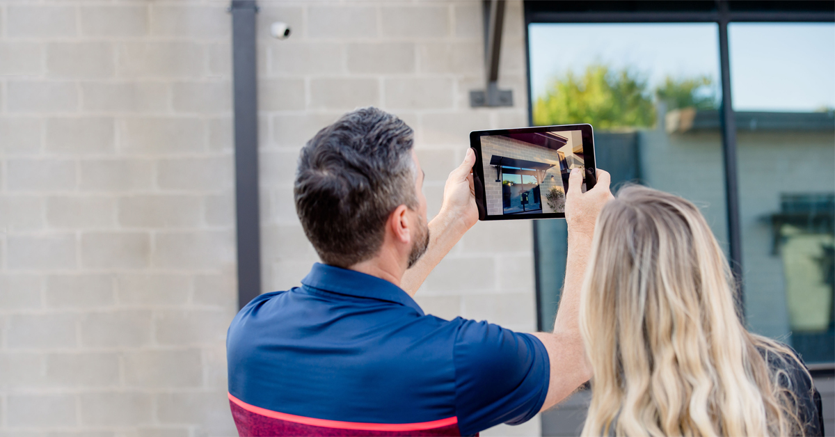 Two property inspectors using a tablet to take photos of a building's exterior.