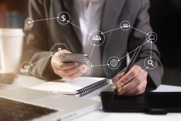 A business person using a smartphone with a digital overlay of connected business icons.