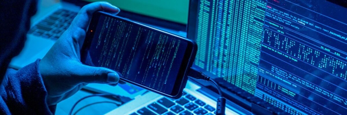 Hand holding a smartphone in front of a computer screen displaying lines of code.