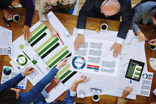 An overhead view of a business team reviewing financial charts and graphs spread across a table.