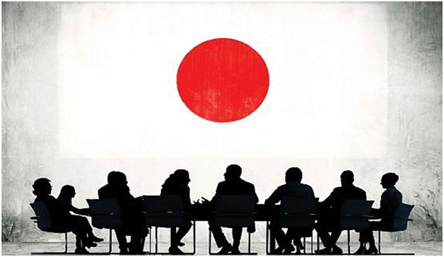 Silhouettes of a board meeting in front of a large, projected flag of Japan.