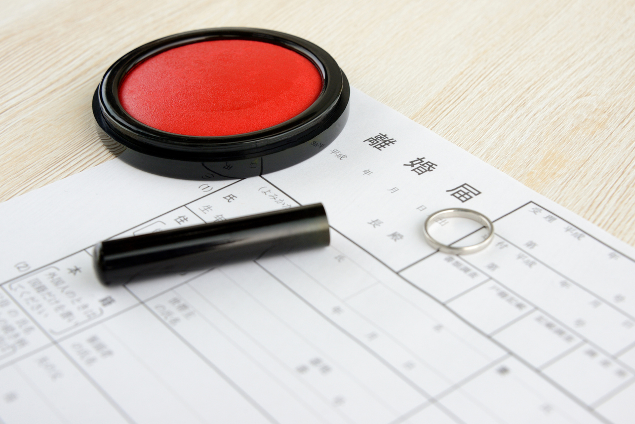 A Japanese divorce form (rikon todoke) with a wedding ring and a traditional hanko stamp and ink pad.