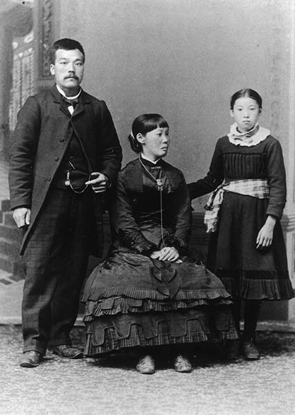 A vintage black and white studio portrait of a Japanese family from the Meiji era.