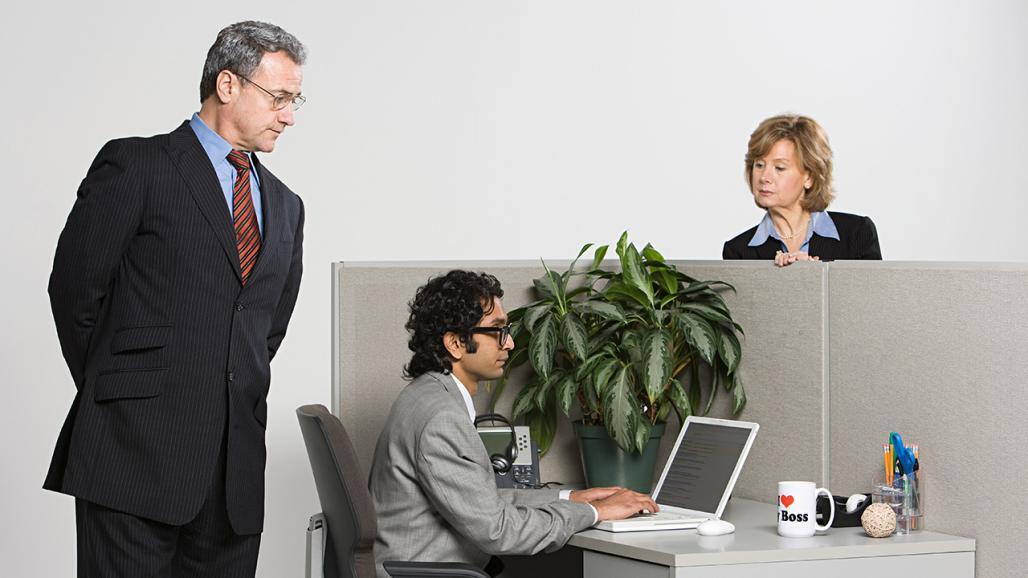 A man in a suit looks over his shoulder suspiciously while hiding a document in his jacket.