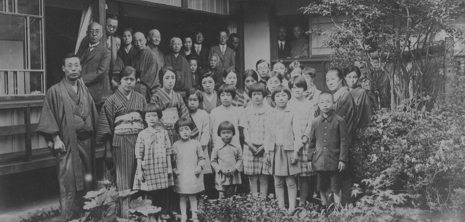 An old, black and white photograph of a large Japanese family gathered together.