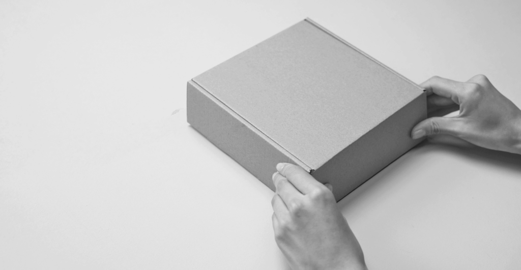 A pair of hands opening a plain cardboard box.