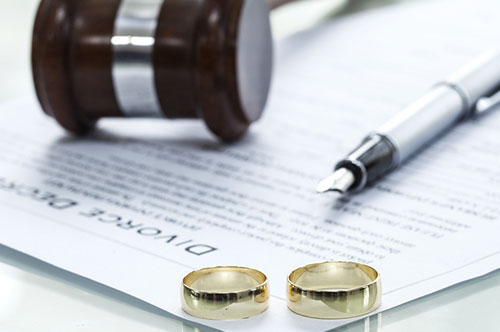 A divorce document on a table with two wedding rings and a judge's gavel.