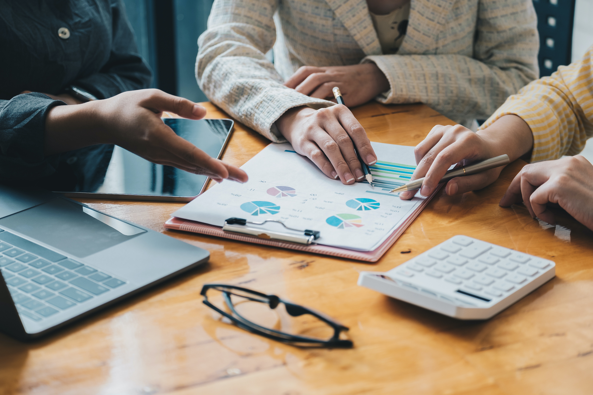 A business team at a wooden table reviewing financial charts and data.