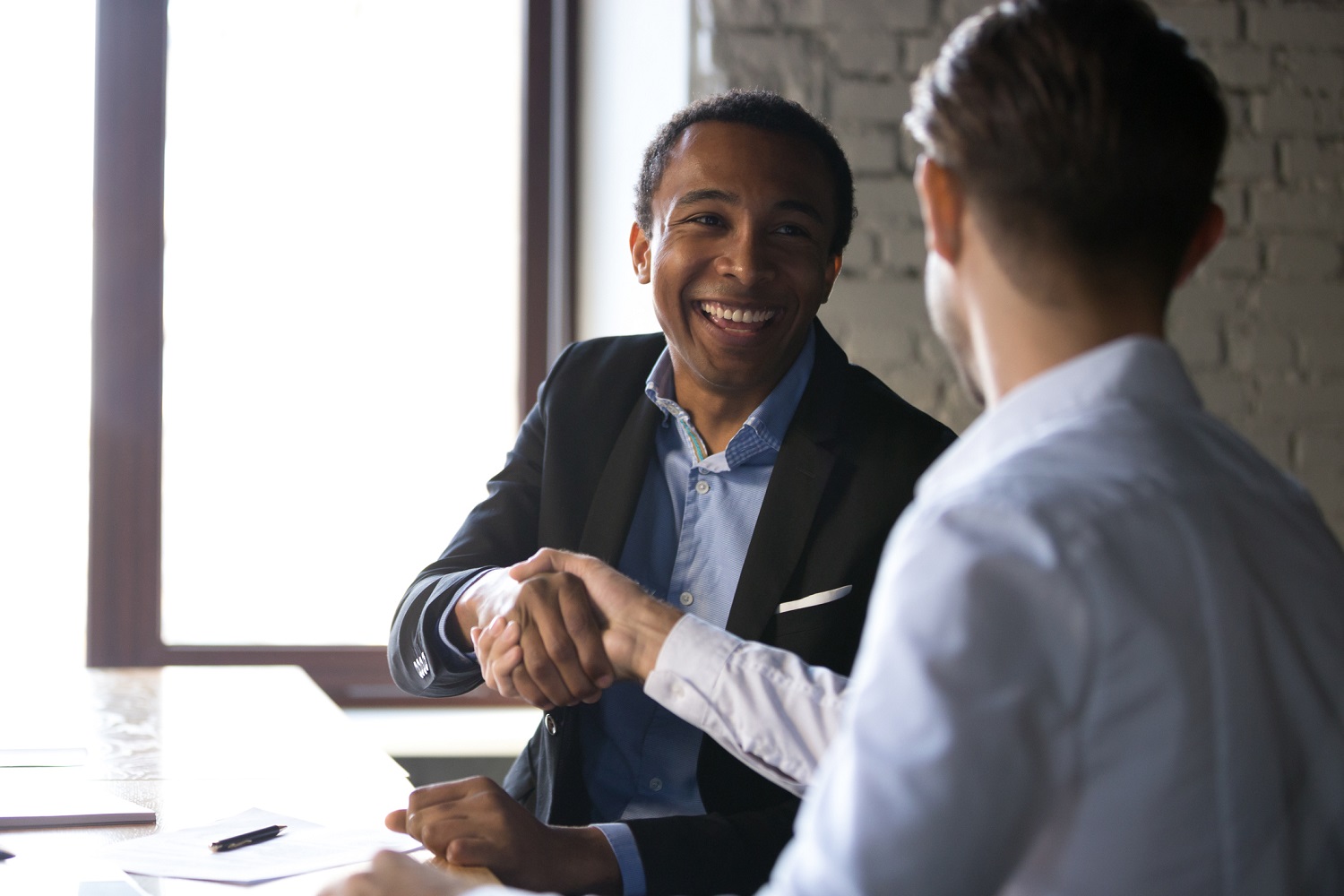 Two smiling businessmen shaking hands in an office.
